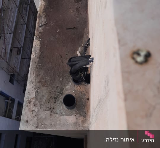 צינורות שחורים על גג בטון עם חור עגול